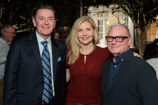 Three people posing for a photo outdoors at night.