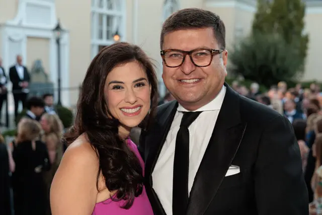Man in glasses and tuxedo with woman in pink dress smiling