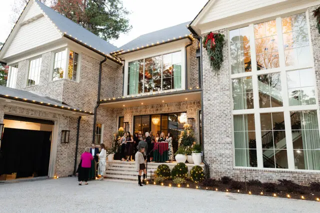 Luxury brick home with white trim, decorated for holidays with lights and greenery.
