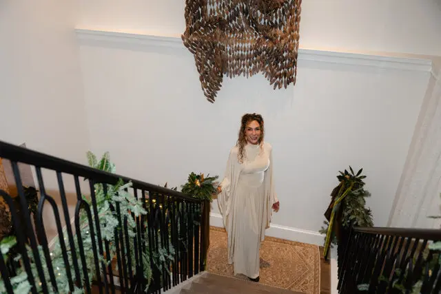 Woman in cream dress on staircase with Christmas garland and abstract wall art