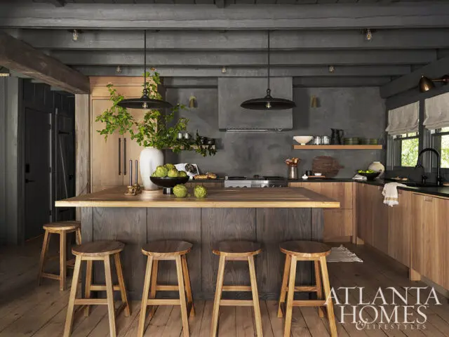 Rustic kitchen with dark wood island, light wood cabinets, and gray concrete walls.