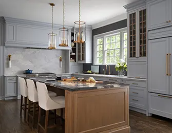 Gray kitchen with marble backsplash, wood island, and brass pendant lights.