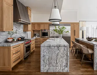 Kitchen with light wood cabinetry, marble countertops, and stainless steel appliances.
