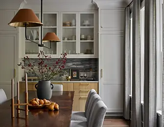 Dining room with dark wood table, gray striped chairs, built-in cabinetry, and brass pendant lights.
