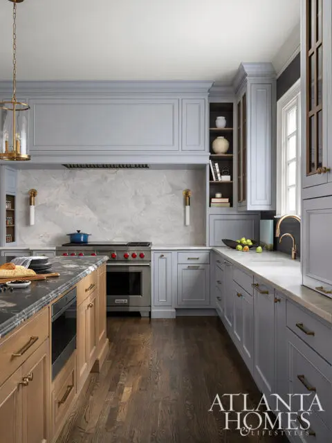 Gray kitchen with marble backsplash, wood island, and brass hardware