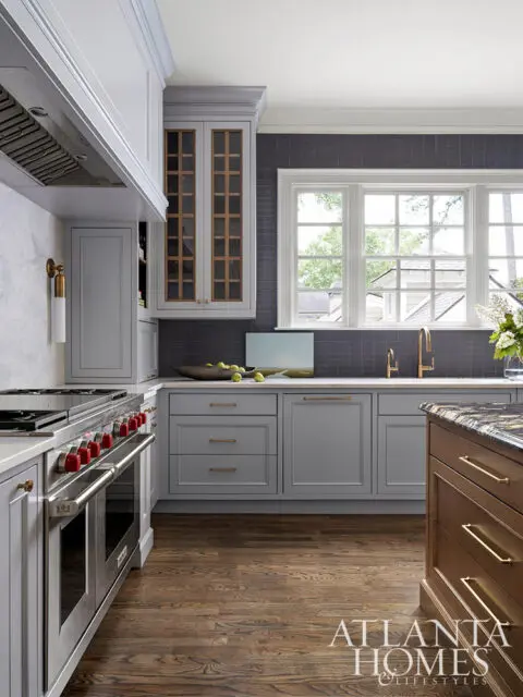 Gray kitchen with stainless steel range, dark tile backsplash, and wood floors.