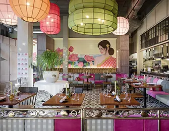 Restaurant dining room with pink and green lanterns, floral mural, and patterned tile floor
