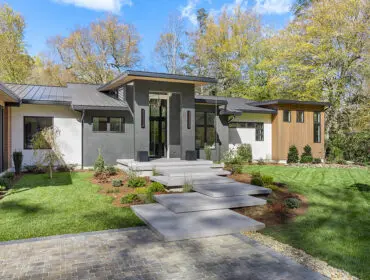Modern home with gray stone facade, wood accents, and floating concrete steps.