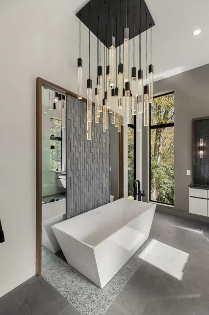 Modern bathroom with freestanding white tub, textured gray wall, and bubble-filled pendant lights.