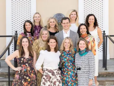 Group portrait of eleven people posing outdoors on steps.