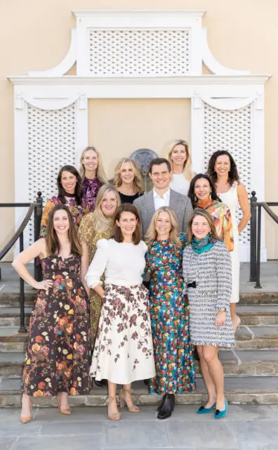 Group of eleven people posing on steps in front of a building.