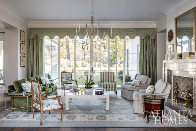 Living room with green sofa, floral chairs, striped armchair, and marble fireplace.