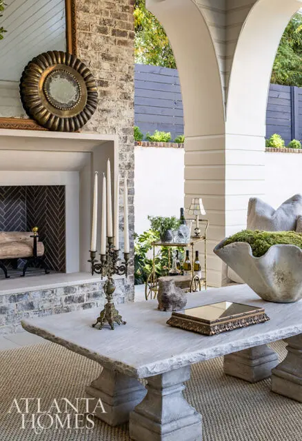 Stone coffee table with candelabra, bar cart, and large shell planter.