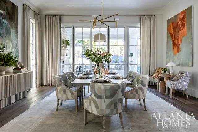 Dining room with a table set for eight, upholstered chairs, and large glass doors.