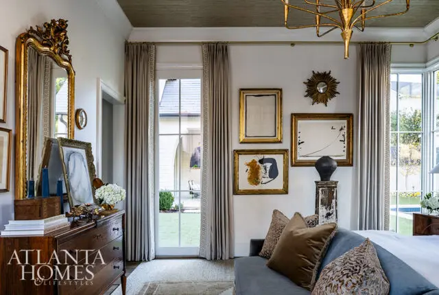 Bedroom with gray walls, gold mirror, abstract art, and blue sofa.