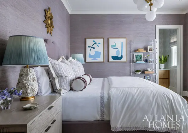 Purple textured wallpaper bedroom with white bedding, blue lamps, and abstract art.