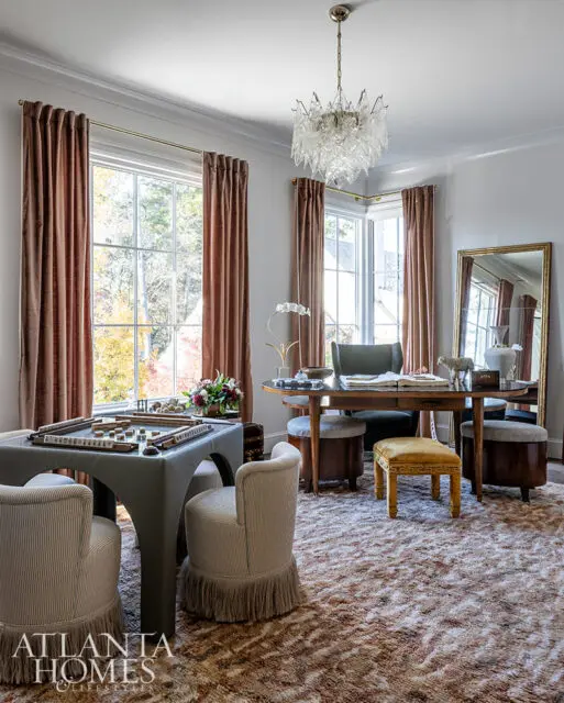 Game room with mahjong table, striped chairs, ornate chandelier, and patterned rug.