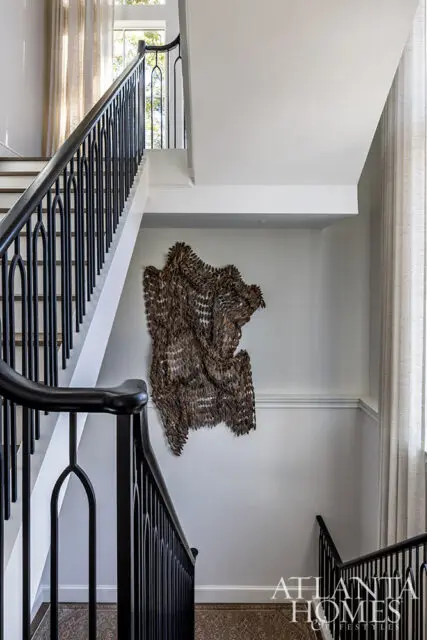 Staircase with black railings and a textured wall art. Atlanta Homes & Lifestyles logo visible.