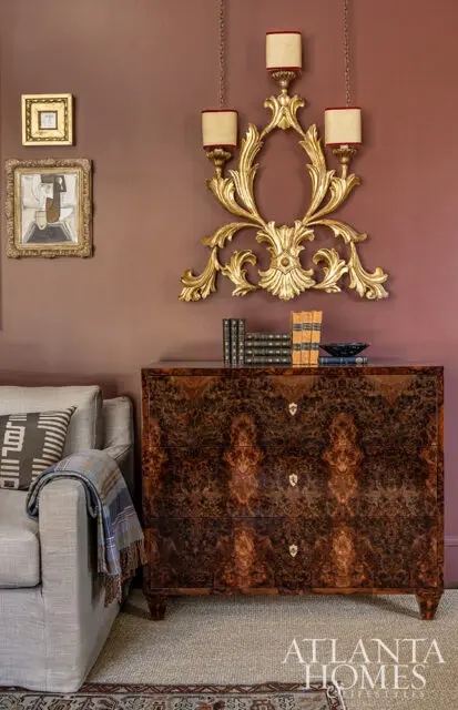 Brown burl wood dresser with gold hardware, next to a gray sofa with patterned pillows.