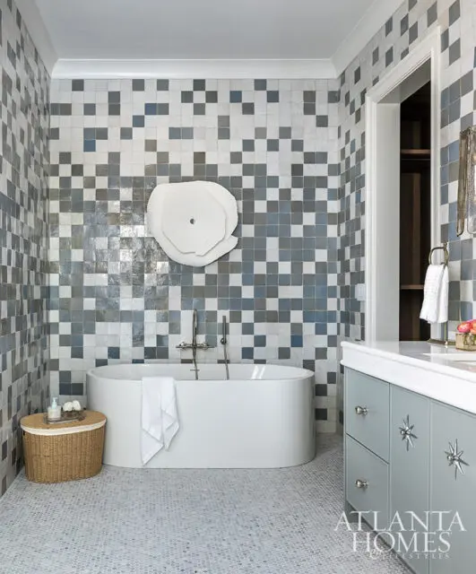 Bathroom with blue and gray checkerboard tile, freestanding tub, and gray vanity with starburst