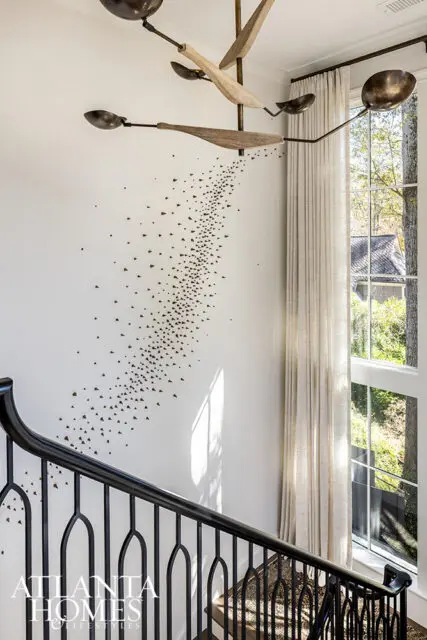 Staircase with black railing, abstract wall art, and large window with sheer curtains