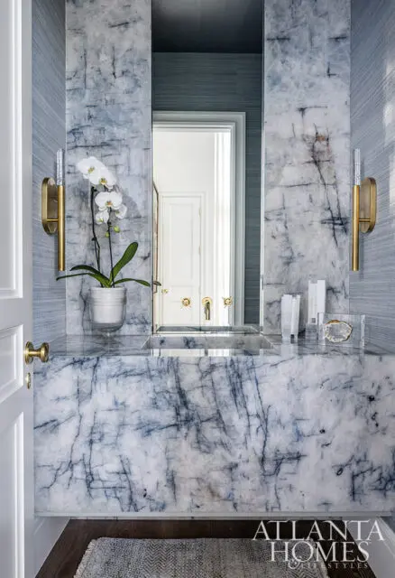 Powder room with blue marble vanity, integrated sink, and grasscloth wallpaper.