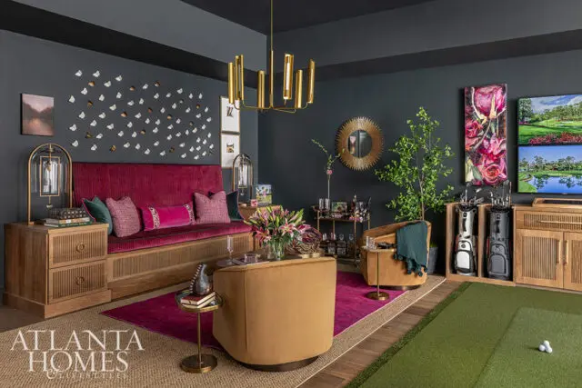 Living room with dark walls, magenta sofa, gold chandelier, and golf putting green