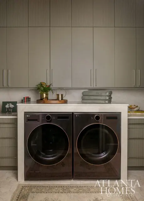 Laundry room with two black LG washers and dryers, gray cabinetry, and marble countertop.