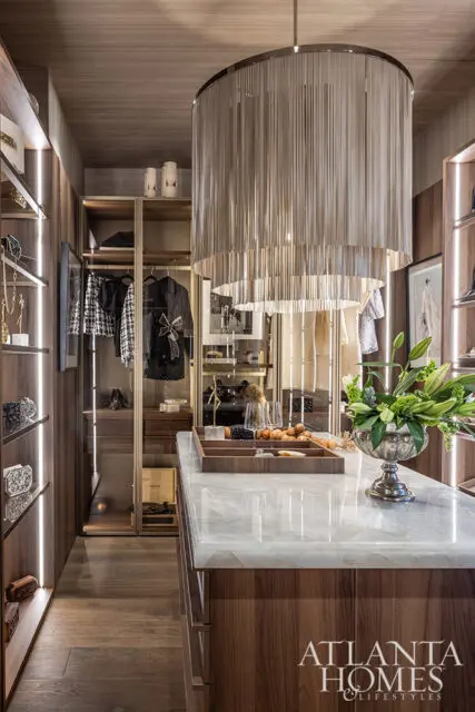 Walk-in closet with wood cabinetry, marble island, and tiered chain chandelier.