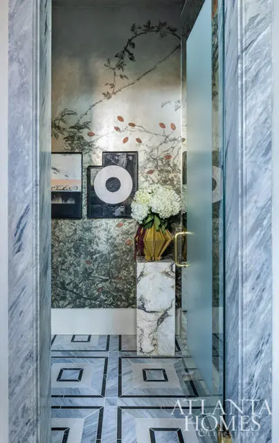 Hallway with marble floors, botanical wallpaper, and framed art. Frosted glass door.