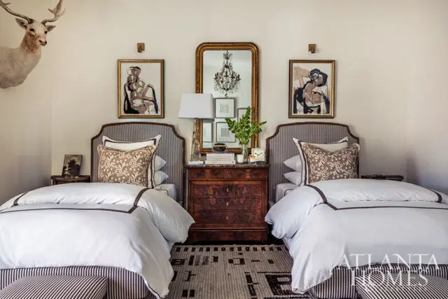 Bedroom with two twin beds, striped headboards, white bedding, and a mounted deer head.