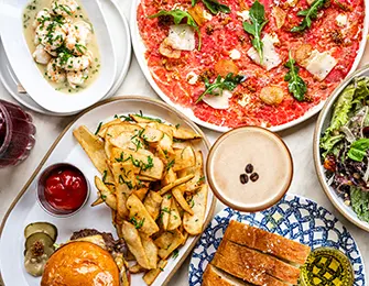 Assortment of food including shrimp, carpaccio, fries, burger, salad, bread, and coffee