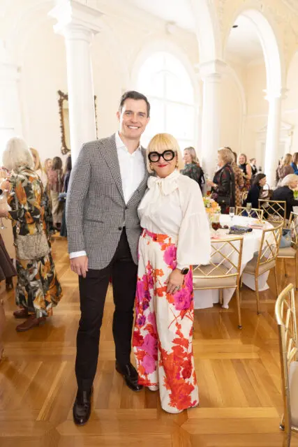 Man in a plaid jacket and woman in a floral skirt smiling at an event.
