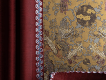 Gold dragon wallpaper with red trim and velvet cushion.