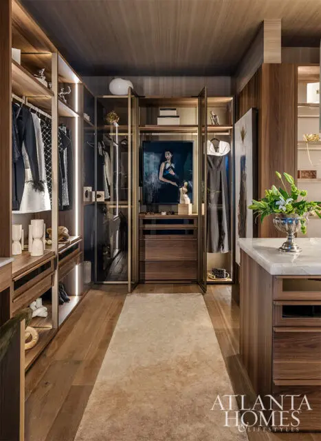 Walk-in closet with dark wood cabinetry, marble island, and artwork.