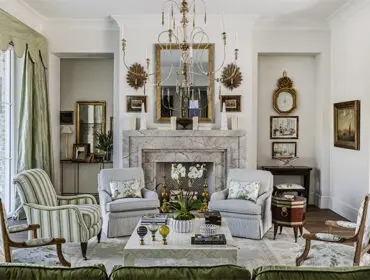 Living room with marble fireplace, striped armchairs, floral upholstered chairs, and ornate