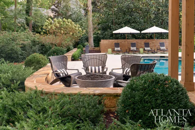 Stone patio with chairs, fire pit, and pool