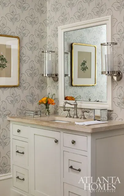 Bathroom vanity with cream cabinetry, beige countertop, and floral wallpaper.