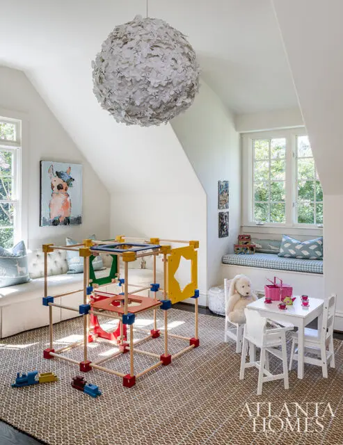 Children's playroom with a large flower chandelier, fort structure, and toy table.