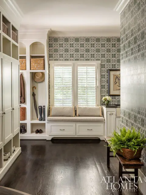 Mudroom with built-in storage, window seat, and patterned wallpaper.