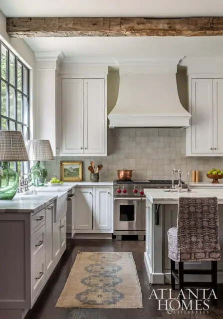 White kitchen with marble countertops, stainless steel range, and exposed wood beam