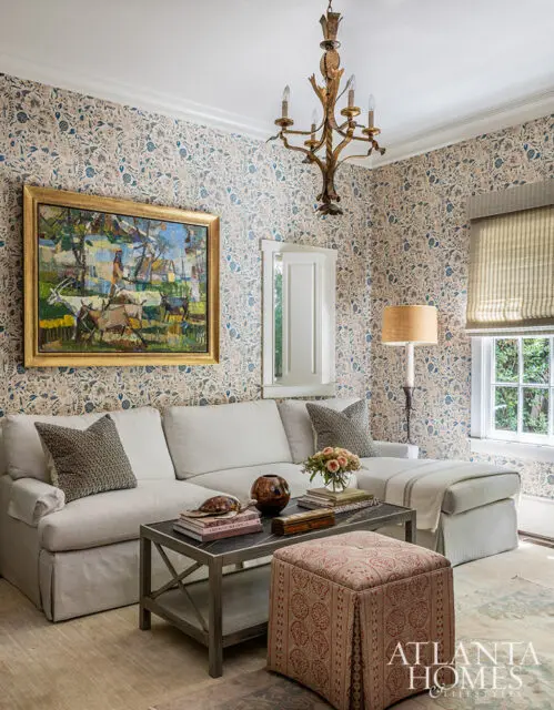 Living room with floral wallpaper, sectional sofa, and ornate chandelier.