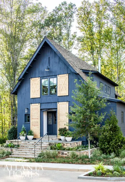 Blue house with wood barn doors and stone steps surrounded by trees