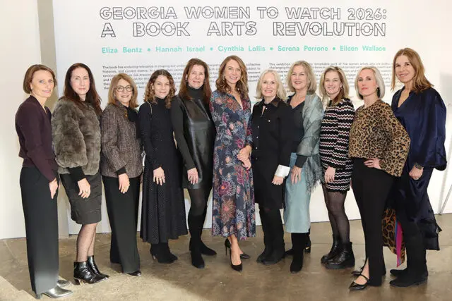 Group portrait of ten women standing in front of a wall with text that reads 'GEORGIA WOMEN TO WATCH 2026: A BOOK ARTS REVOLUTION' and names including Eliza Bentz, Hannah Israel, Cynthia Lollis, Serena Perrone, and Eileen Wallace.