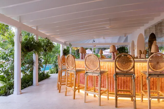 Bar with rattan stools, textured orange counter, and wicker lamps.