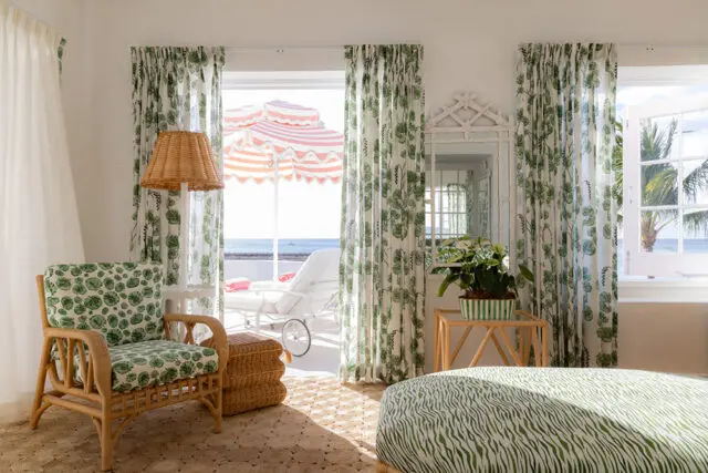 Rattan armchair with green leaf pattern cushions, wicker ottoman, and green zebra print ottoman.
