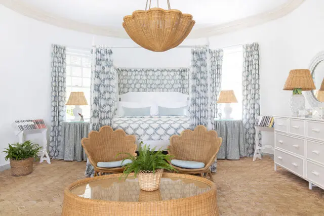 Bedroom with canopy bed, rattan chairs, wicker furniture, and blue and white patterned curtains.