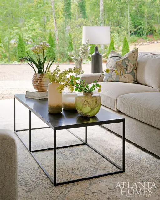 Living room with neutral sofa, black coffee table, patterned rug, and decorative vases.