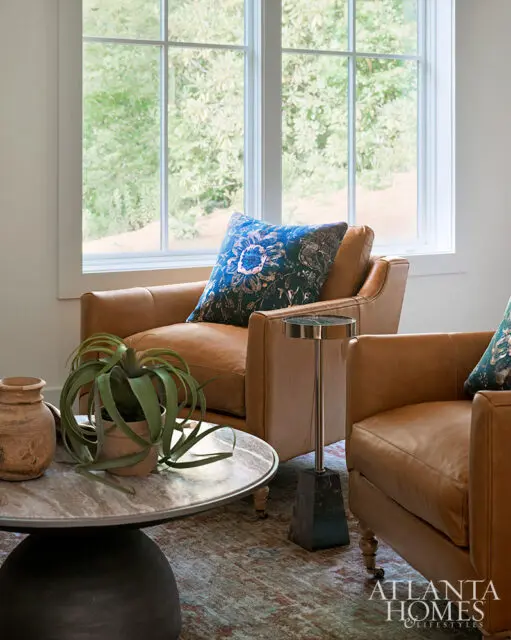 Living room with two tan leather armchairs, a marble coffee table, and a dark blue patterned pillow.