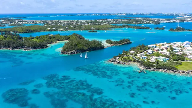 Aerial view of Bermuda with turquoise water, sailboats, and colorful houses on islands.
